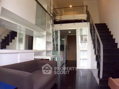Modern loft apartment with mezzanine bedroom and sleek black staircase.