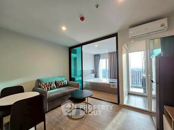 Modern apartment with open living room and bedroom, featuring a balcony with city view.