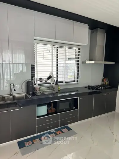 Modern kitchen with sleek cabinets and gas stove, featuring a stylish open layout and elegant flooring.