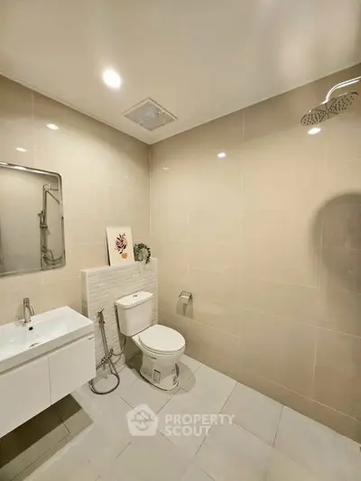 Modern bathroom with sleek fixtures and neutral tiles, featuring a spacious shower area.