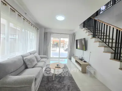 Modern living room with stylish decor and large windows, featuring a cozy sofa and wall-mounted TV.