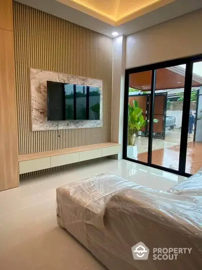 Modern living room with sleek TV setup and large glass doors opening to patio.