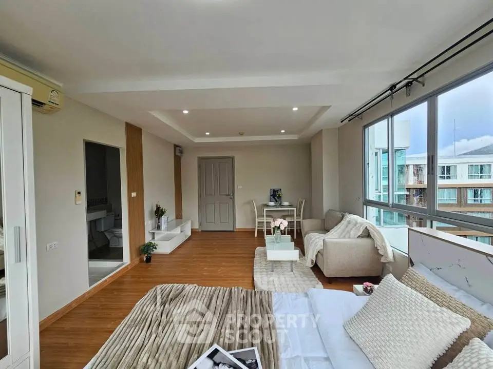 Spacious modern living room with large windows and cozy seating area in a stylish apartment.