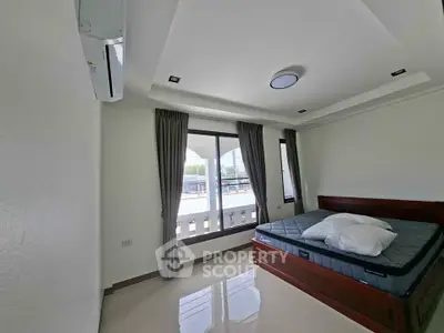 Spacious bedroom with large windows and modern furnishings in a bright apartment.