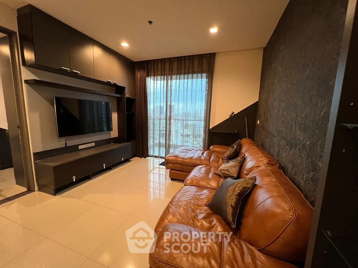 Luxurious living room with leather sofa and modern entertainment center, featuring floor-to-ceiling windows.