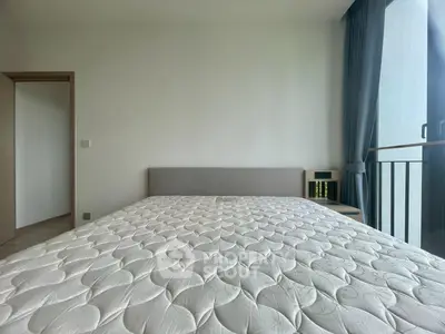 Spacious bedroom with large window and modern decor in a contemporary apartment.