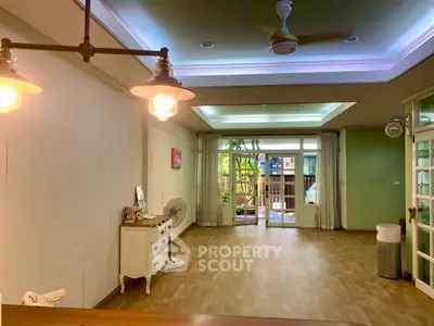 Spacious living room with elegant lighting and large windows opening to a garden view.