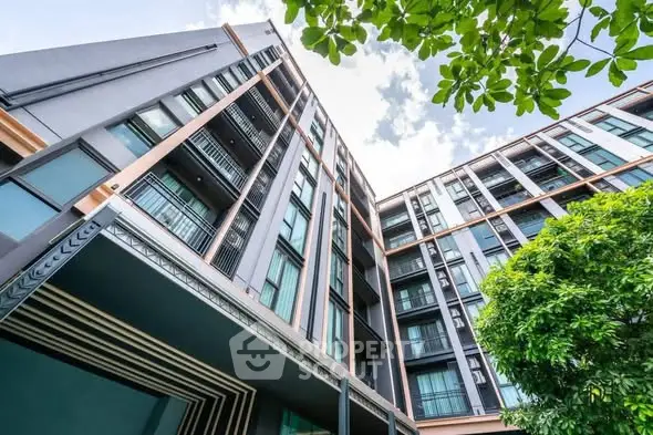 Modern high-rise building with lush greenery and clear blue sky