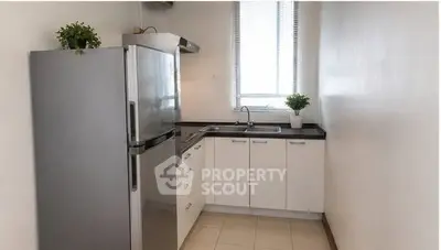 Modern kitchen with sleek appliances and minimalist design, featuring a stainless steel fridge and ample counter space.