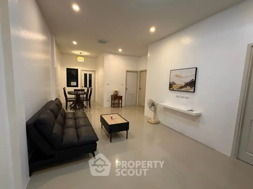 Spacious modern living room with sleek black sofa and elegant dining area