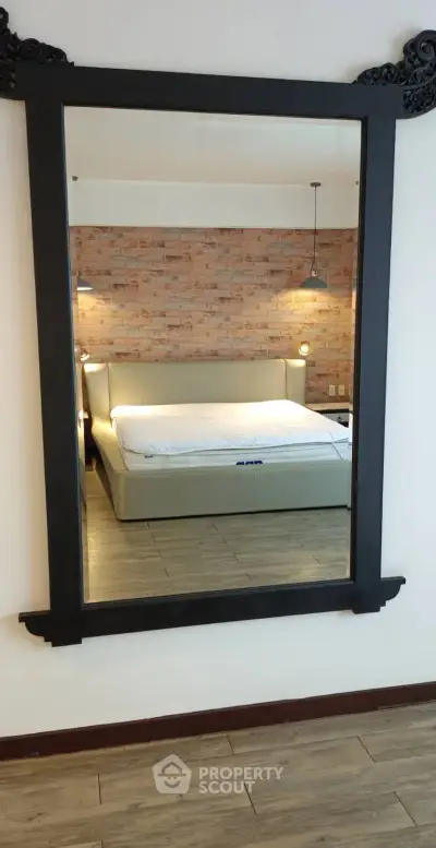 Stylish bedroom with modern decor and cozy bed reflecting in a large mirror, perfect for relaxation.