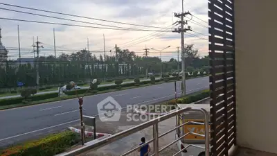Spacious balcony with street view and lush greenery, ideal for relaxation.