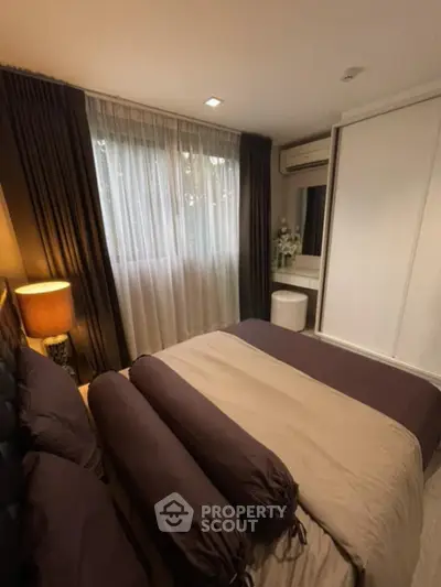 Cozy bedroom with elegant decor and ample natural light from large window.