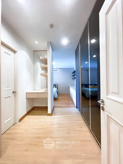 Spacious modern bedroom with wooden flooring and sleek mirrored closet doors.