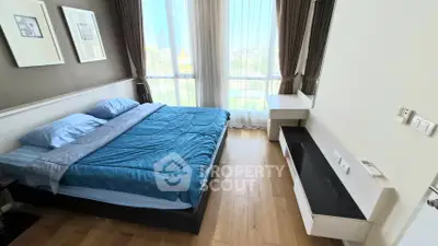 Modern bedroom with large window and stylish decor in a high-rise apartment.