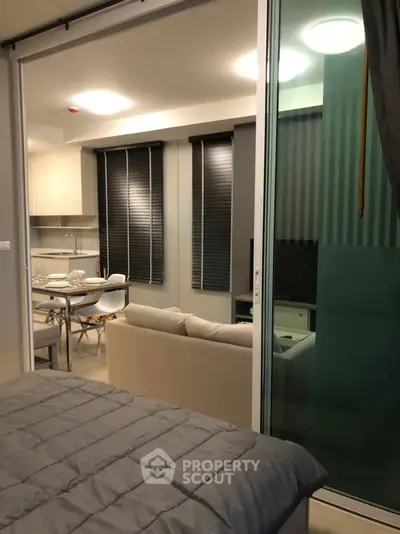Modern open-plan living room with kitchen and dining area, featuring sleek design and cozy ambiance.