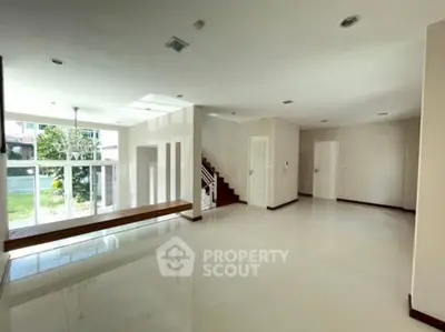 Spacious modern living room with large windows and staircase