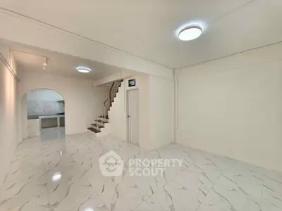 Spacious open-plan living area with modern staircase and marble flooring