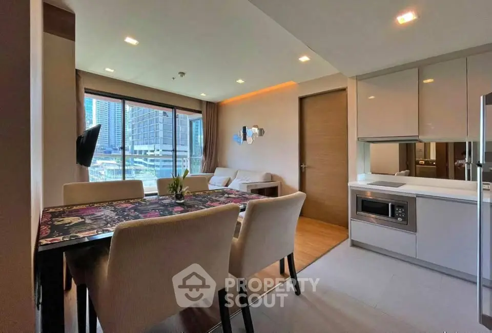 Modern open-layout living room and kitchen with city view, stylish dining area, and sleek appliances.