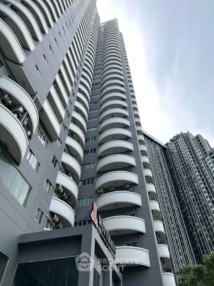 Modern high-rise building with curved balconies and sleek design.