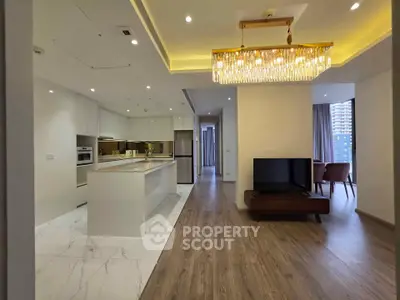 Luxurious open-plan kitchen and living room with modern chandelier and elegant flooring.