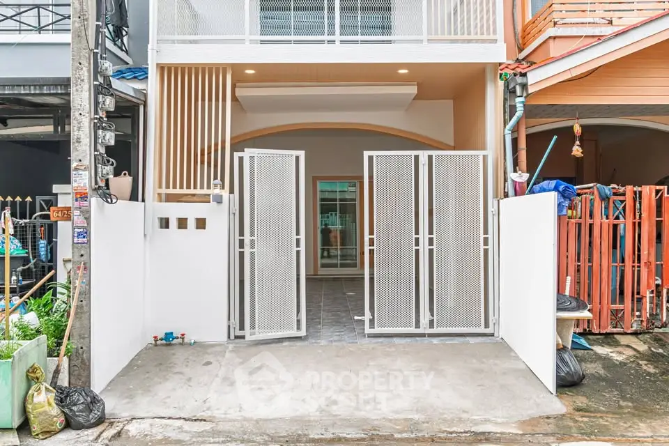 Modern townhouse entrance with sleek metal gate and clean facade