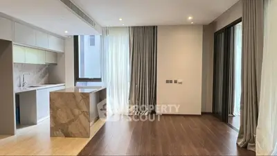 Modern open-plan kitchen and living area with marble island and floor-to-ceiling windows.