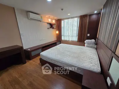 Spacious bedroom with modern wooden furniture and large window for natural light.