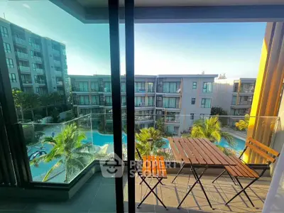 Stunning balcony view overlooking a luxurious pool and modern apartment complex, perfect for relaxation.