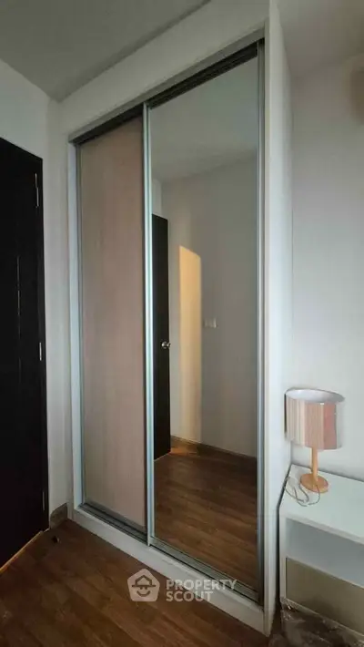 Modern bedroom with sleek sliding wardrobe and stylish lamp on wooden floor.