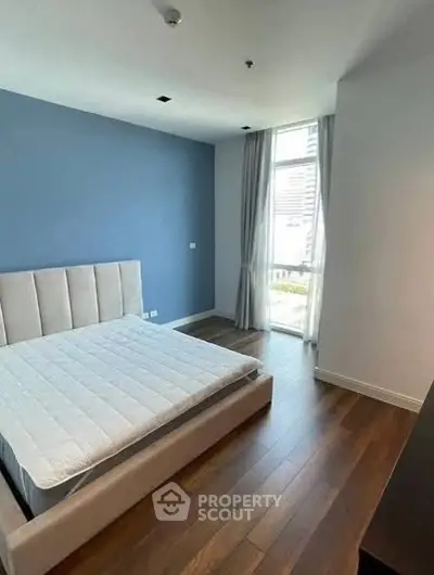 Spacious bedroom with modern design and large window offering natural light.