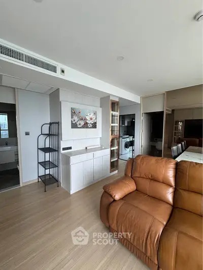 Modern living room with leather sofa and open kitchen in stylish apartment