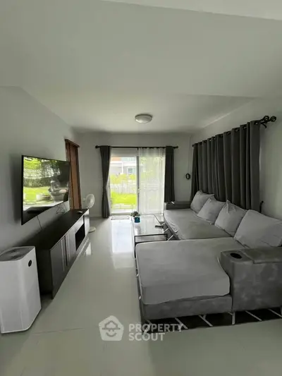 Spacious living room with modern gray sofa and large TV, perfect for relaxation and entertainment.