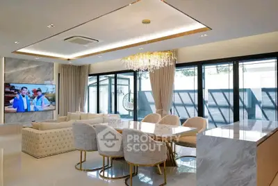Luxurious open-plan living and dining area with elegant chandelier and modern decor.