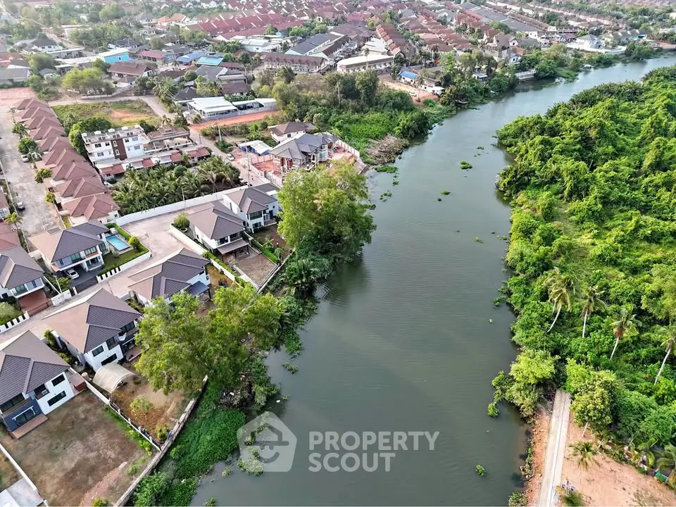 Aerial view of riverside residential community with lush greenery and modern homes.