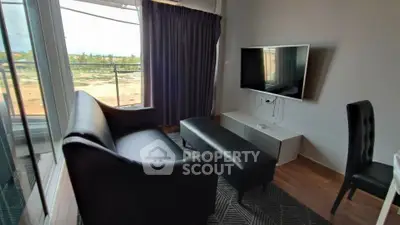 Modern living room with sleek black furniture and large window offering scenic views.