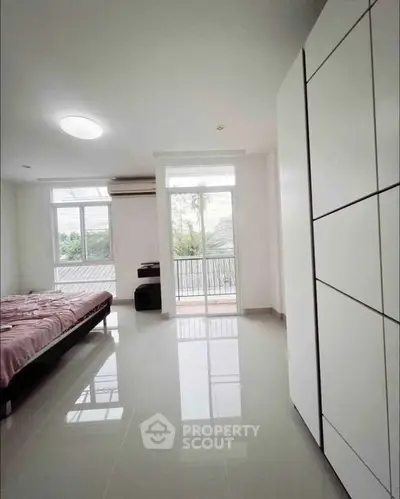 Spacious bedroom with large windows and balcony access, offering a bright and airy atmosphere.