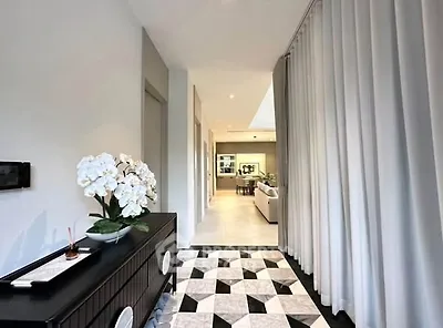 Elegant hallway with modern decor leading to a spacious living area, featuring stylish flooring and ambient lighting.
