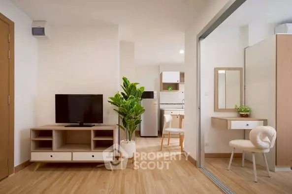 Modern living room with TV, stylish furniture, and open kitchen layout in a cozy apartment.