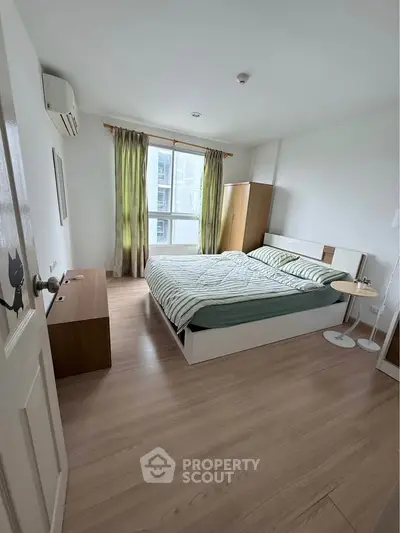 Spacious bedroom with modern furnishings and large window offering natural light in a stylish apartment.
