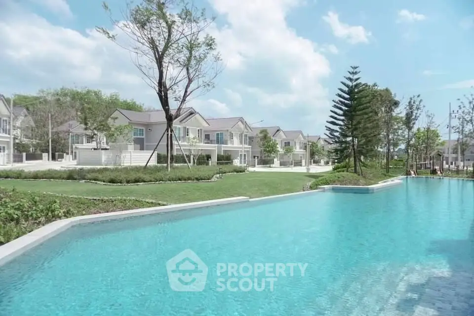 Luxurious residential community with pristine pool and modern homes under blue skies.