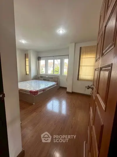 Spacious bedroom with large windows and wooden flooring, perfect for natural light lovers.