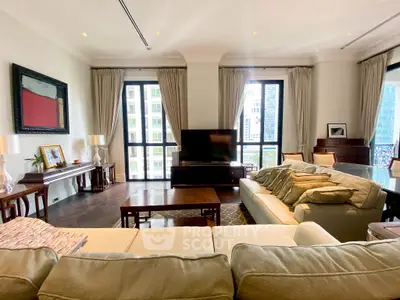 Spacious living room with elegant decor and large windows offering city views.