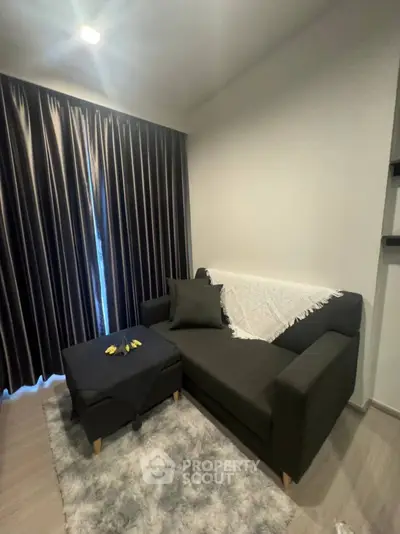 Cozy living room with dark sofa and elegant curtains, perfect for relaxation.