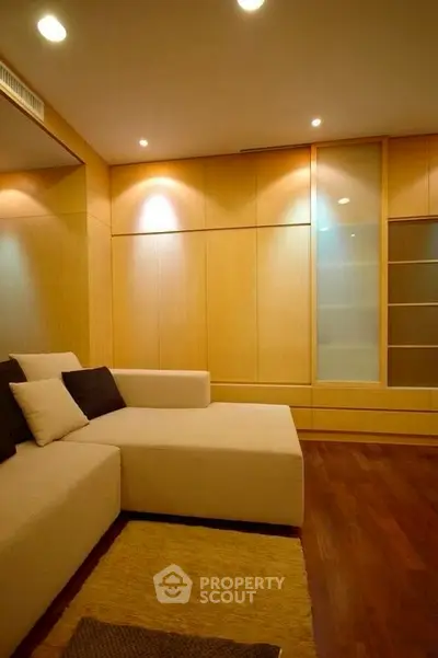 Modern living room with stylish beige sectional sofa and warm wooden paneling