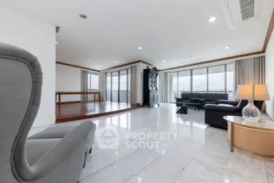 Spacious living room with marble floors and panoramic city views, featuring elegant furniture and abundant natural light.