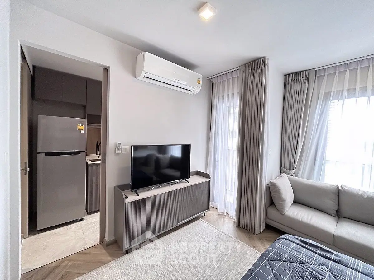Modern living room with air conditioning and natural light, featuring a cozy sofa and sleek TV setup.