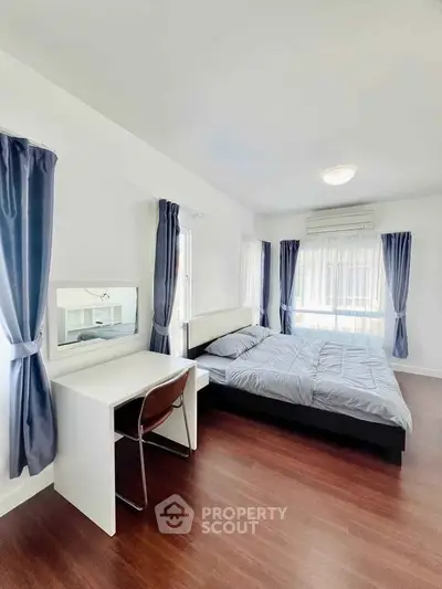 Spacious bedroom with modern decor and natural light, featuring a cozy bed and study desk.