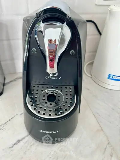 Modern kitchen with sleek espresso machine and kettle on marble countertop.