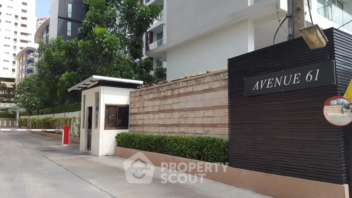 Modern residential building entrance with Avenue 61 sign and security booth.
